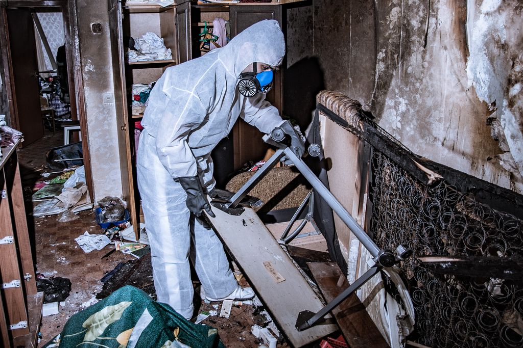 Technicien en combinaison de protection lors du déblaiement d'une maison sinistrée