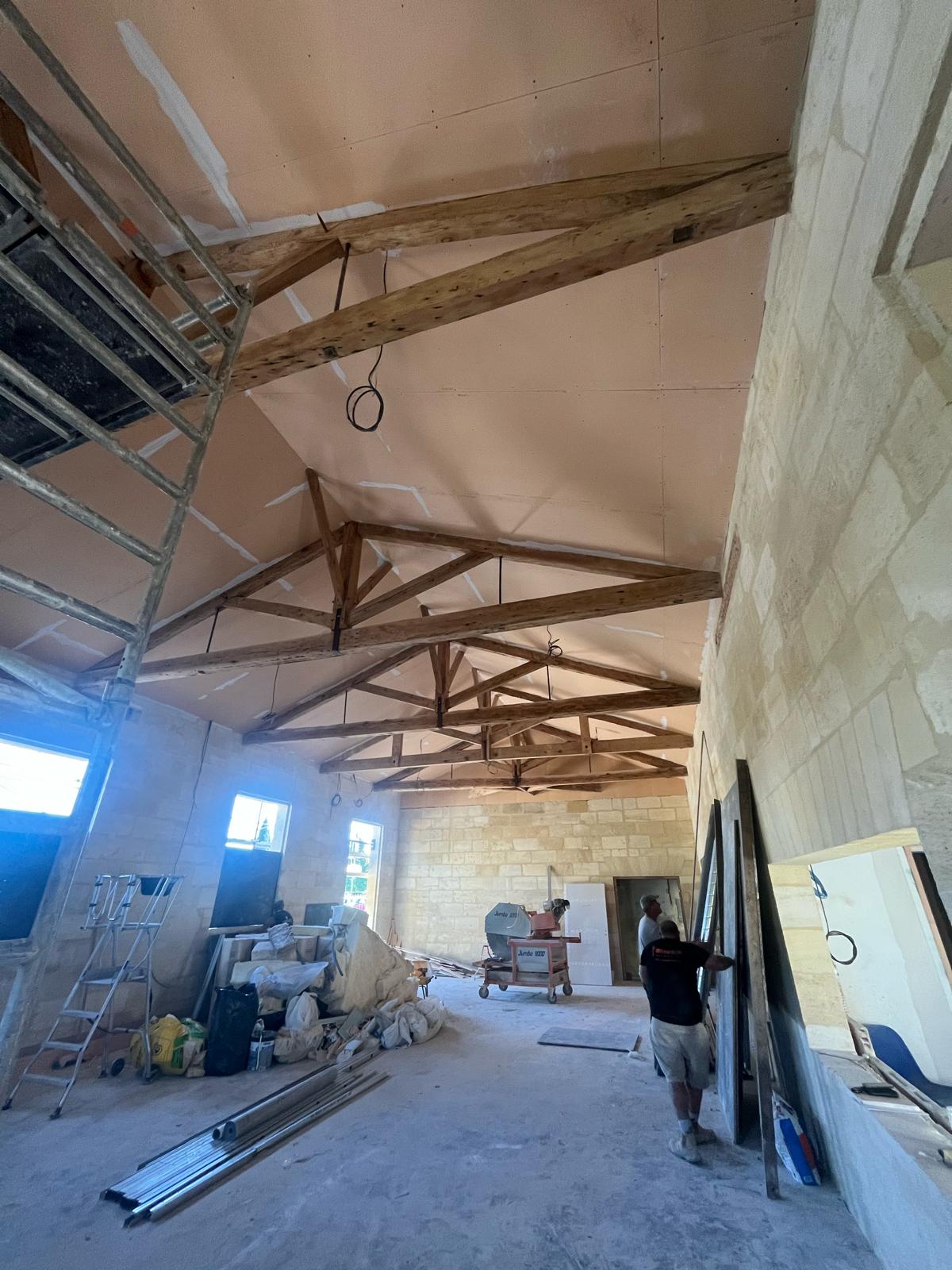 Travaux d'isolation intérieure réalisés par un professionnel équipé sur un chantier à Saumos
