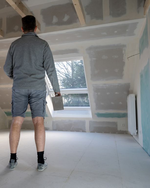 Artisan plaquiste dans des combles aménagés, bandes et enduits en cours de finition