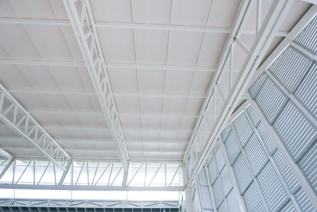 Faux plafond en panneaux posé sous charpente métallique dans un grand volume